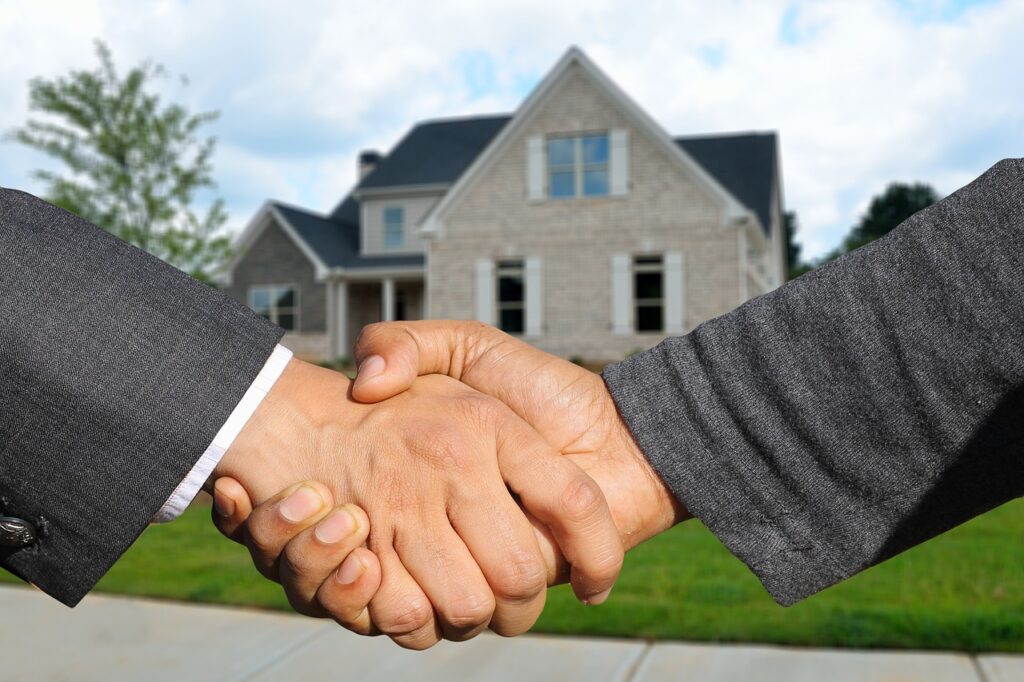 Une poignée de main avec un expert ou agent immobilier devant une maison