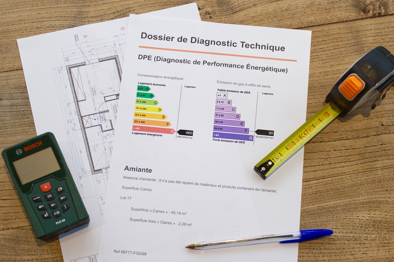 Sur une table, un DPE, avec un stylo, une calculatrice et un mètre sont présentés pour le calcul de la note énergétique d'un logement.